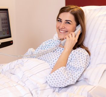 Patientin im Bett beim Telefonieren
