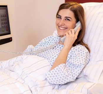 Patientin im Bett beim Telefonieren
