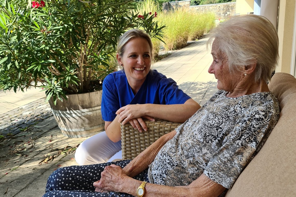 Pflegerin mit Patientin auf Terrasse