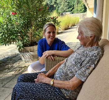 Pflegerin mit Patientin auf Terrasse