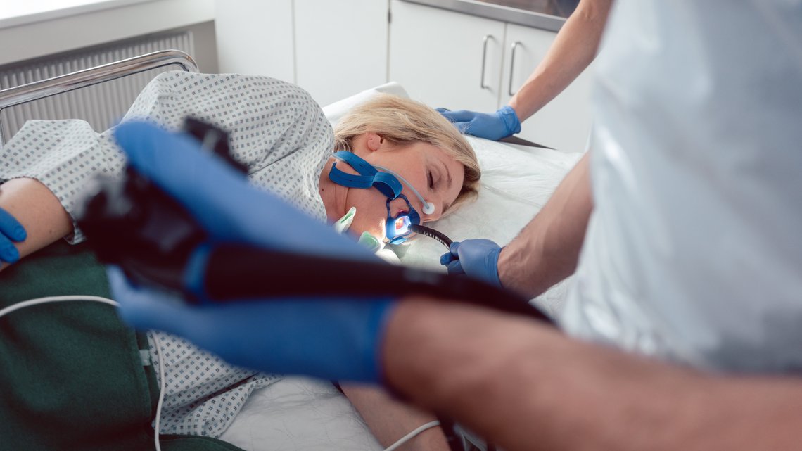 Arzt führt die Kamera von Gastroskop in Mund von Patientin ein