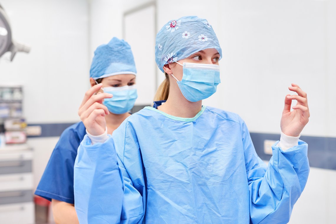Krankenschwester hilft Ärztin beim Kittel anziehen