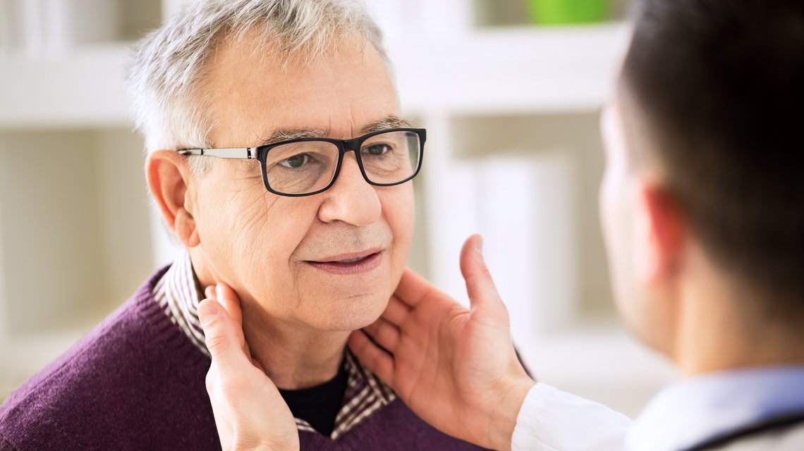 Arzt untersucht die Lymphknoten eines älteren Herrn