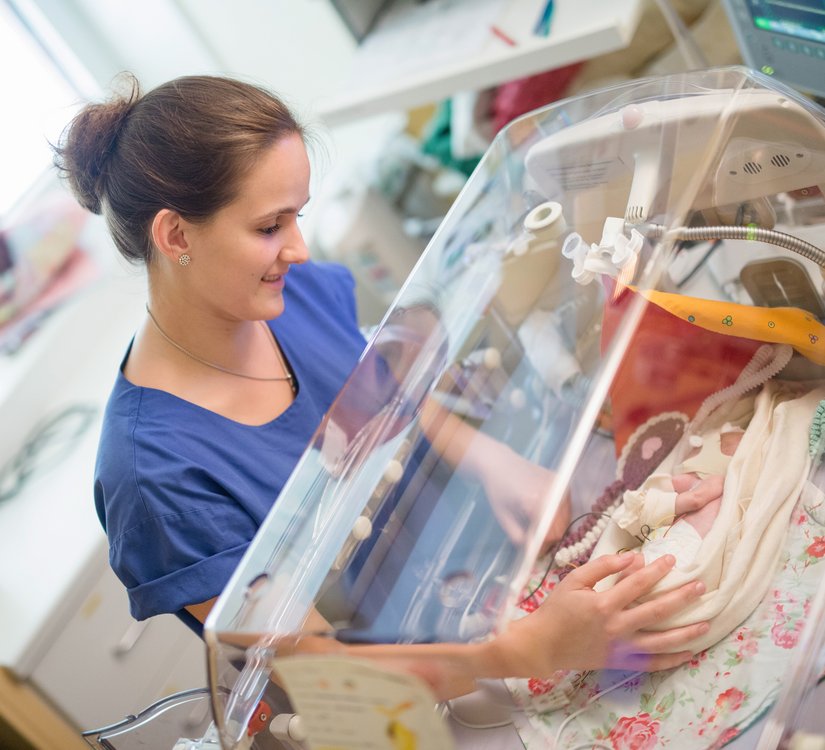 Pflegerin und Säugling im Inkubator