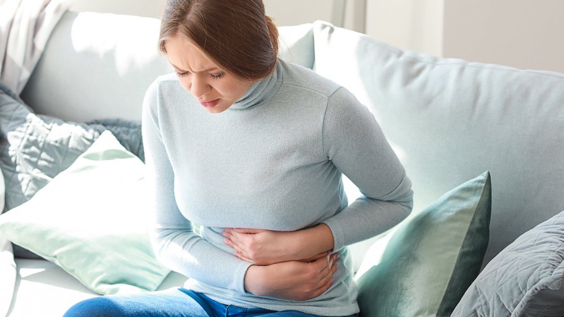 Junge Frau hält sich den Bauch