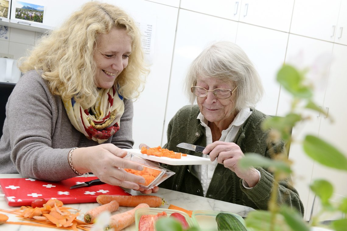 Ältere Dame beim Kochen mit Angehöriger